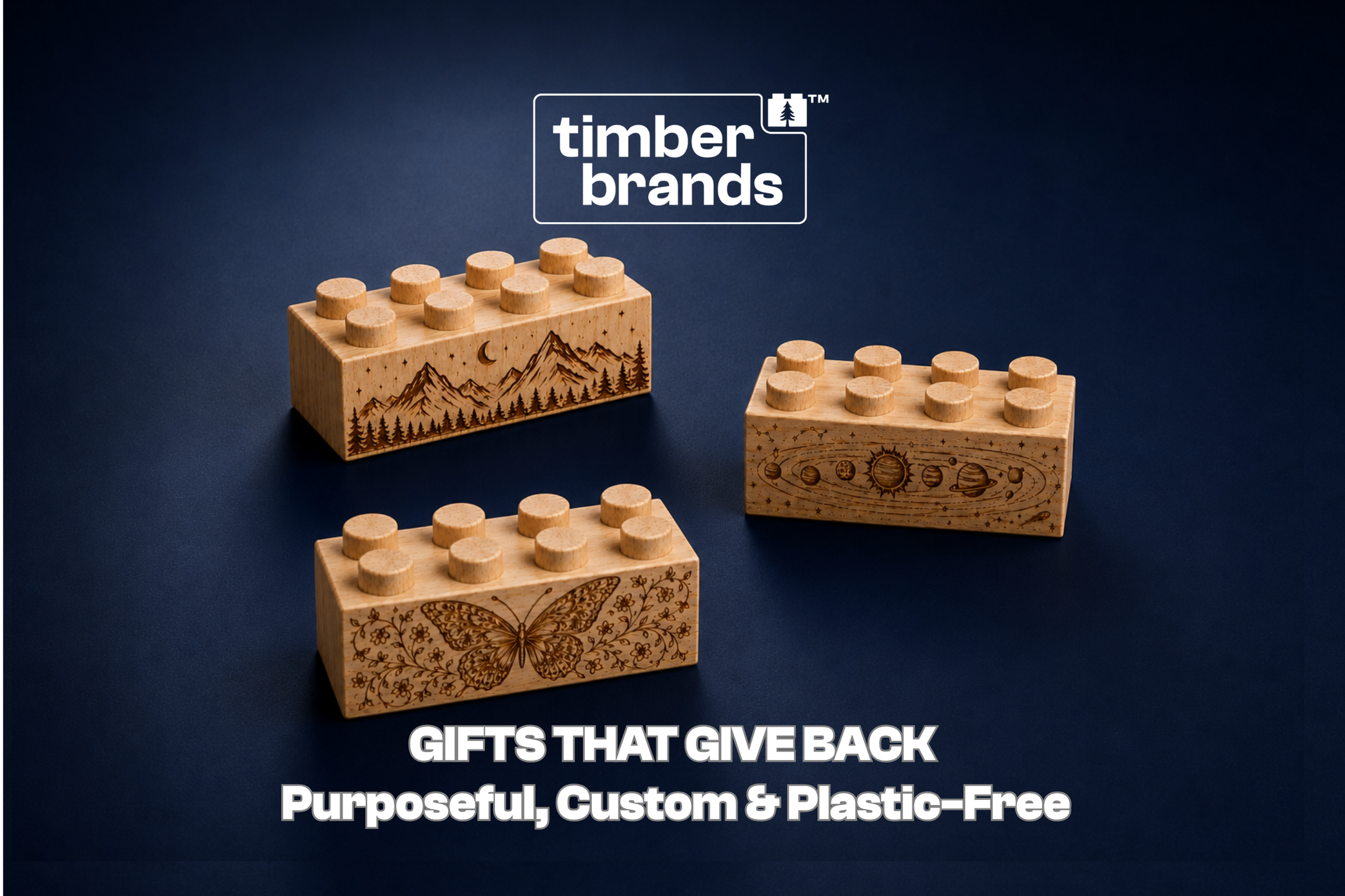 Three Timber Brands wooden building bricks engraved with a detailed mountain landscape, a solar system illustration, and a butterfly design on a dark background, beneath the words "Gifts That Give Back."