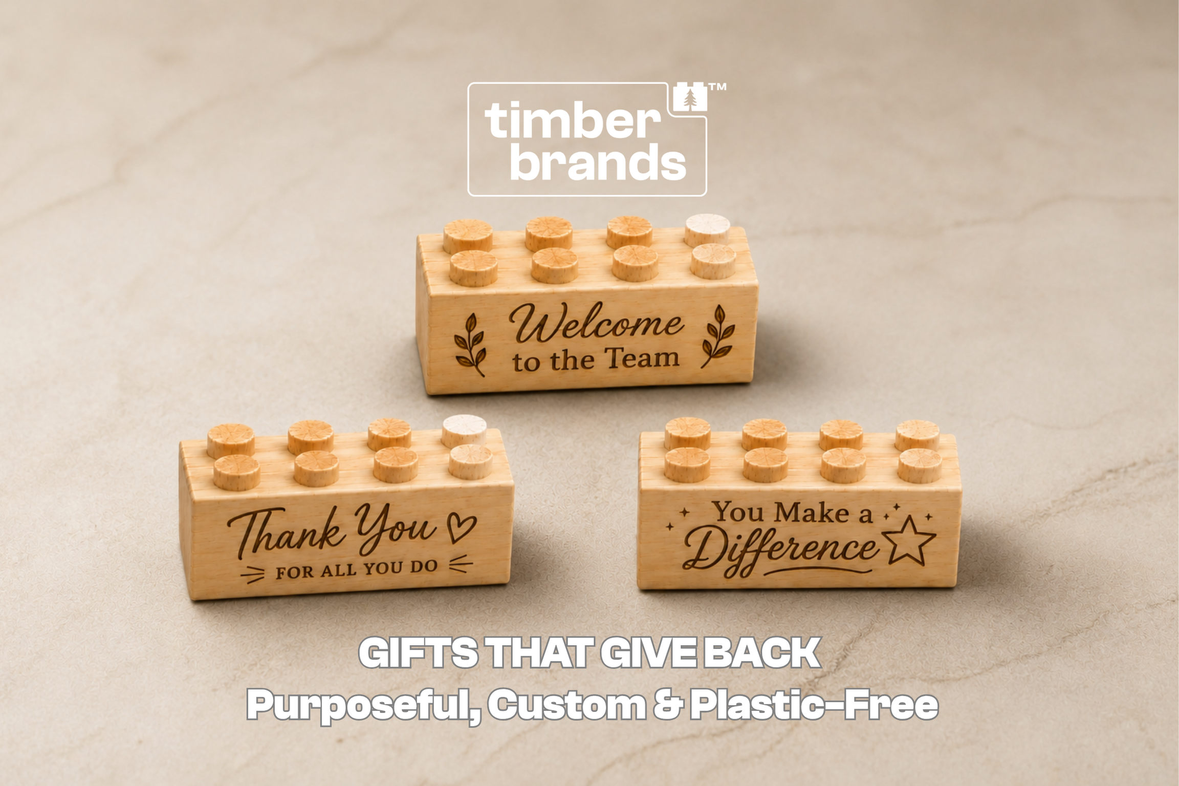 Three Timber Brands wooden building bricks engraved with "Welcome to the Team," "Thank You," and "You Make a Difference" on a neutral stone surface, beneath the words "Gifts That Give Back."