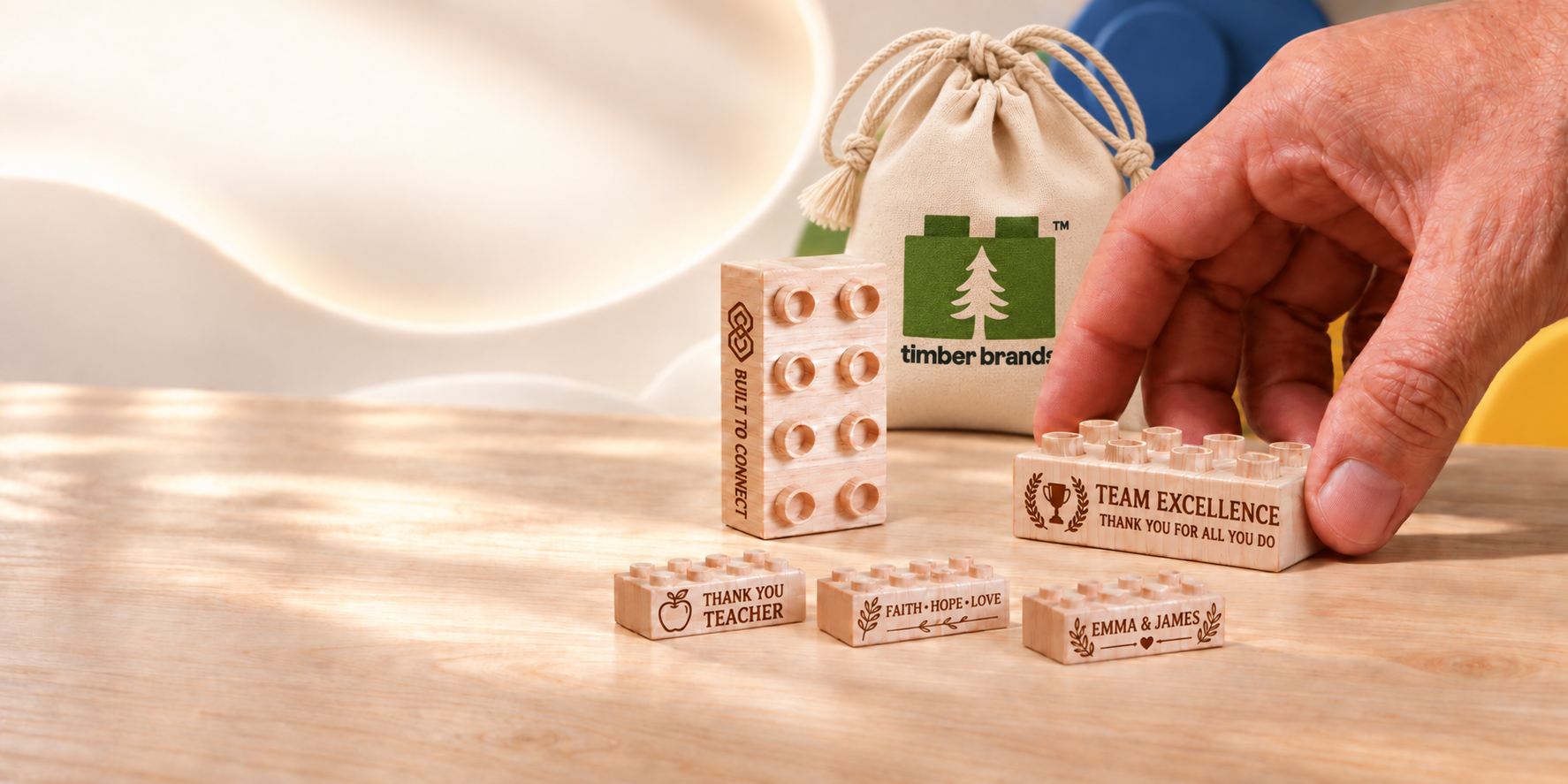 Custom engraved wooden bricks for team recognition, teacher appreciation, faith and weddings beside a Timber Brands drawstring bag.