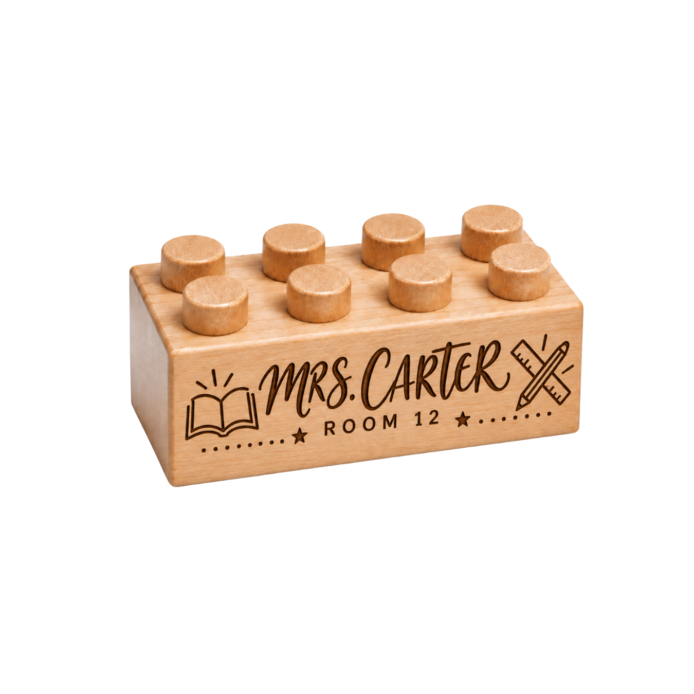 Wooden brick engraved with Mrs. Carter and Room 12, an open book, and a crossed pencil and ruler.
