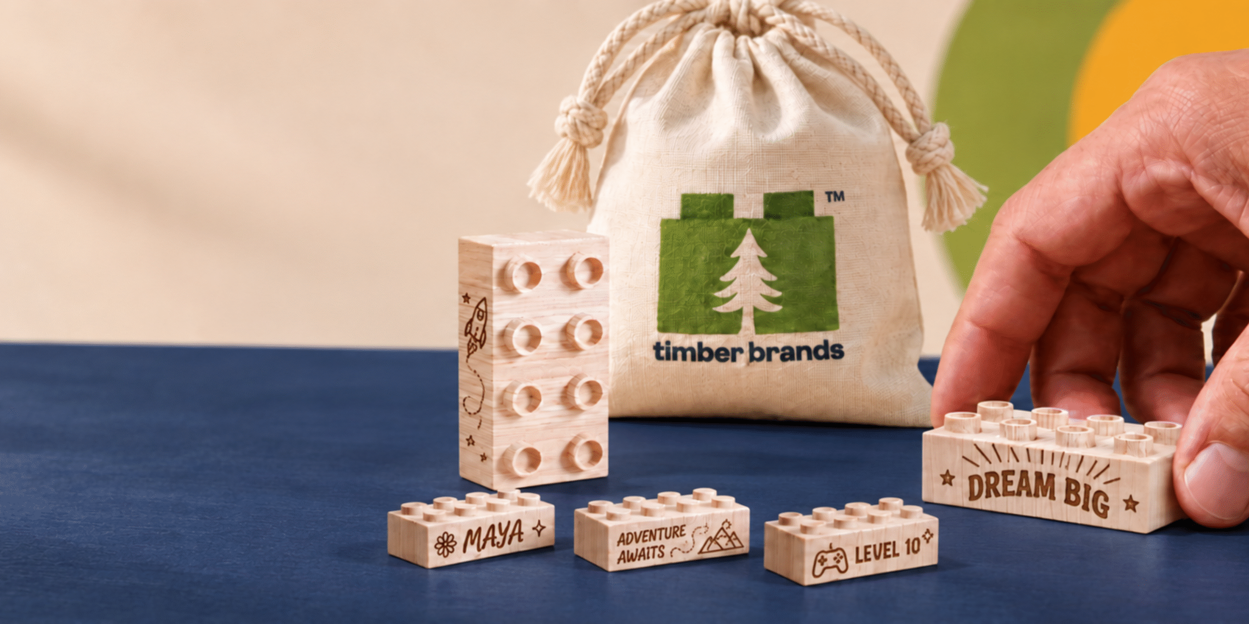 Wooden bricks engraved with business logos and messages beside a Timber Brands drawstring bag